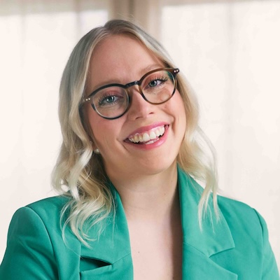 a smiling light entrepreneur named Heini, wearing a mint green blazer with blonde hair and glasses.