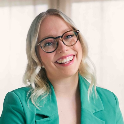 a smiling light entrepreneur named Heini, wearing a mint green blazer with blonde hair and glasses.