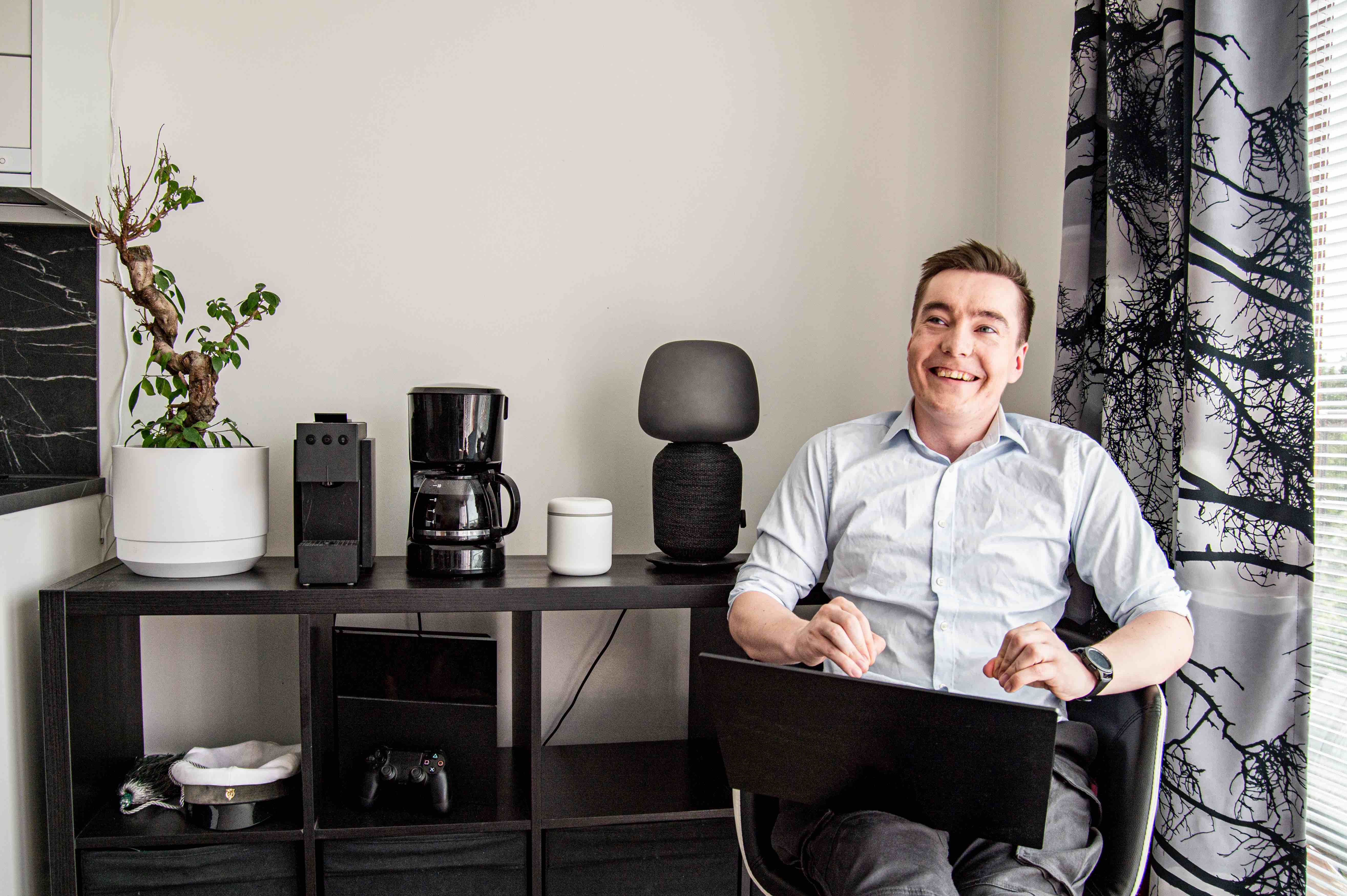 Naurahtava Mikko istumassa modernisti sisustetun keitti&ouml;ns&auml; vieress&auml; l&auml;pp&auml;ri syliss&auml;&auml;n